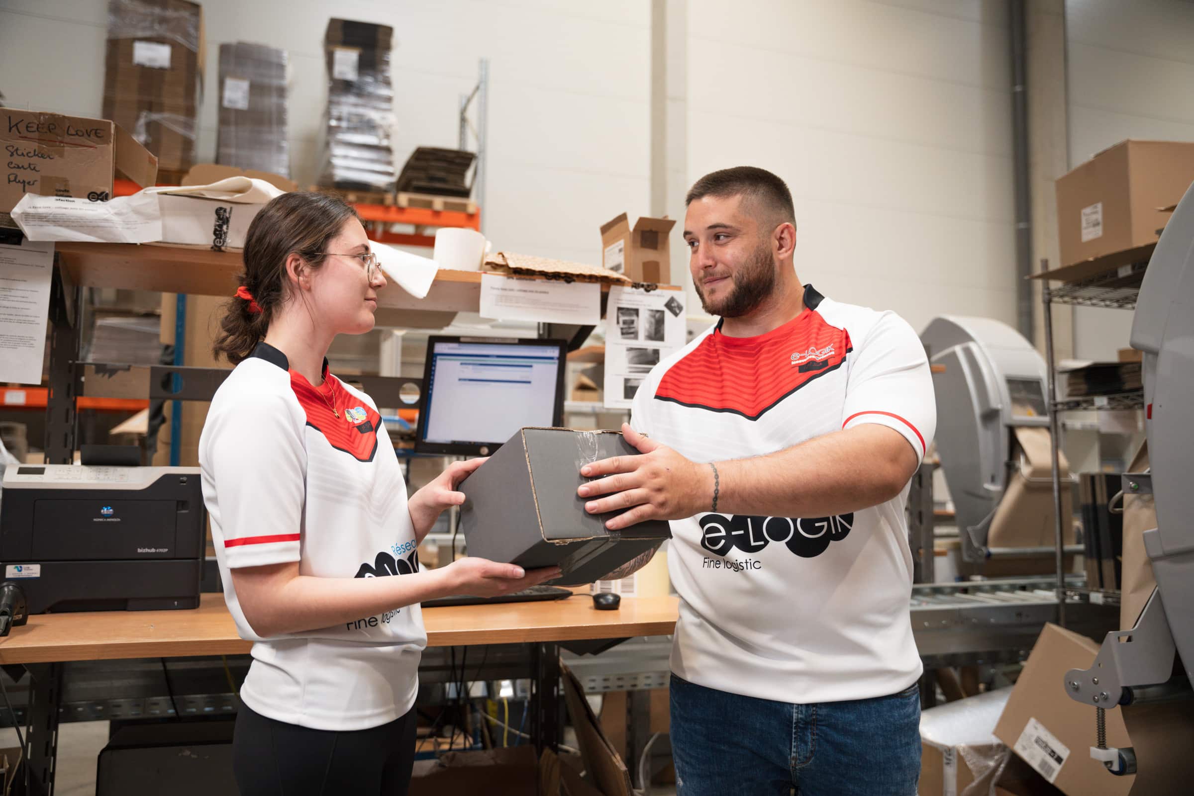 livraison-standard-suivi-tracking (2) Deux salariés d'une entreprise de logistique se passent un colis, illustrant le processus de livraison standard avec suivi tracking pour le e-commerce.